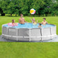 Intex Prism Frame Pool Set featuring a round light gray pool with a white reinforced steel frame, shown on a green lawn with a family playing inside.