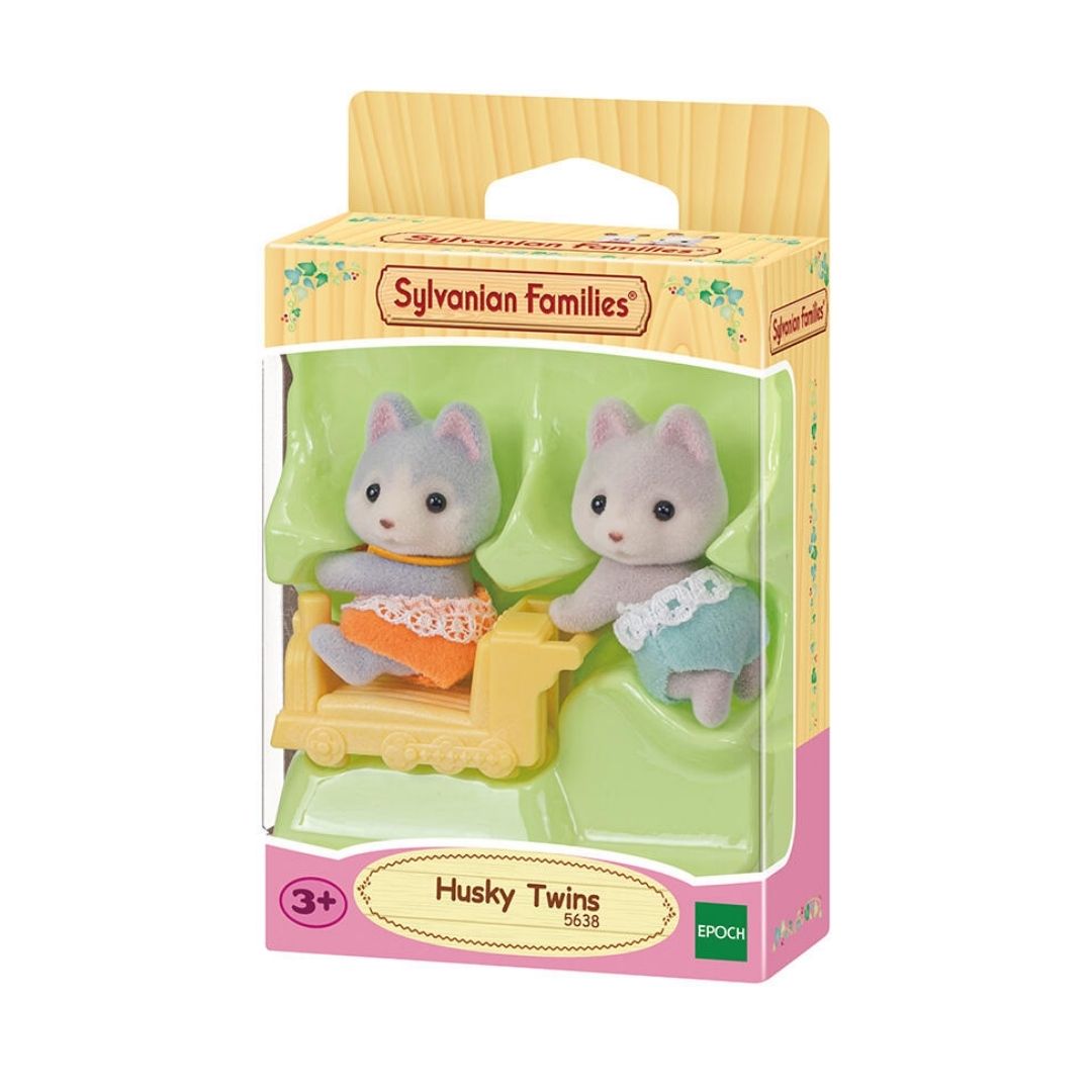 Vibrant multicolor Sylvanian Families Husky Twins featuring two soft-flocked husky puppy figures in amber and silver-blue outfits with a small yellow push-along train toy.