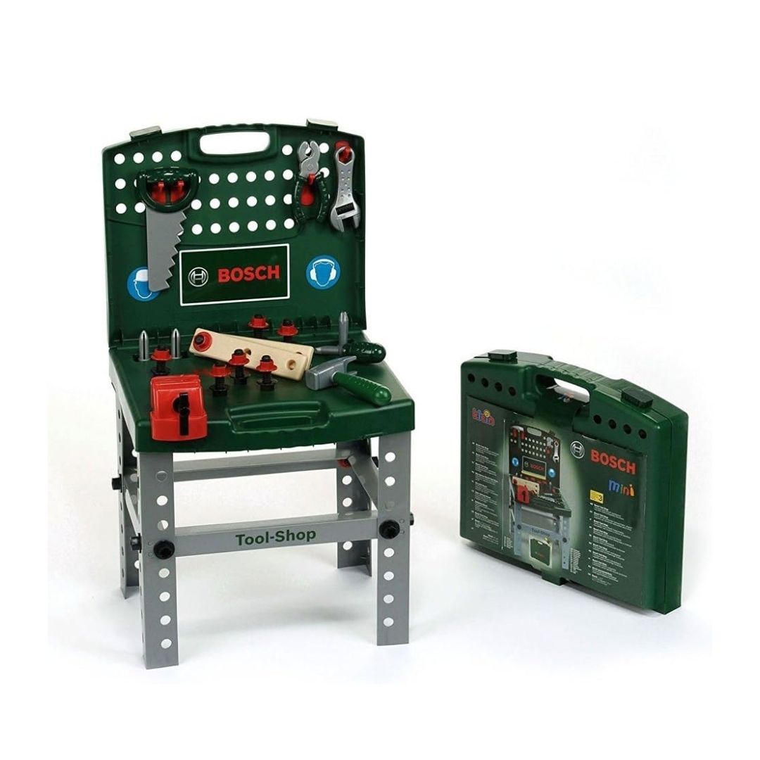 Theo Klein Bosch Tool Shop workbench featuring a dark green tool wall, worktable surface, vise, hand saw, hammer, pliers, spanner, screws, and accessories.